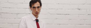 Yakışıklı bir adam moda anlayışını açık beyaz gömlek ve kalın kırmızı kravat ile sergiliyor..