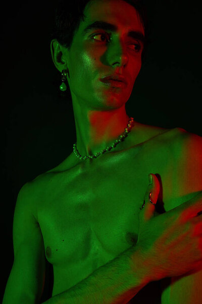 Stylish man showcases bold fashion choices against an artistic green backdrop.