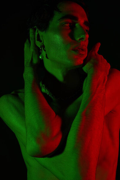 A handsome man poses dramatically against a dark backdrop with colorful lights.