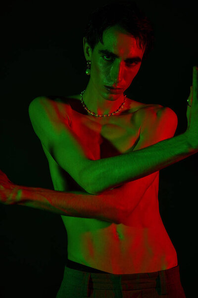 A striking man showcases his unique fashion sense with bold colors and expressive poses in a studio.