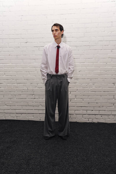 Handsome man wearing formal clothes stands still in a chic atmosphere, showcasing unique fashion.