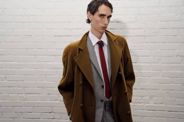 Tarz sahibi bir adam kendine güvenerek dikiliyor, şık bir ortamda moda karizması yayıyor..