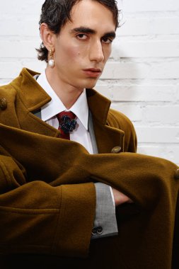 Modern bir ortamda moda anlayışını sergileyen şık bir adam şık kahverengi bir ceket giyer..