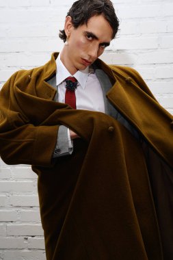 Şık bir adam ceketini düzeltirken kendine güvenerek modaya uygun kıyafetini gösterir..