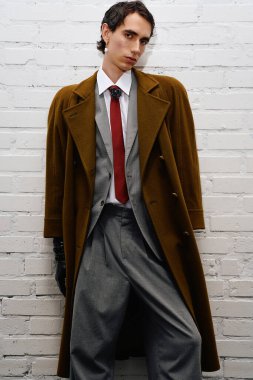 Beyaz tuğladan bir duvara karşı duran kendine güveni tam bir şahıs..