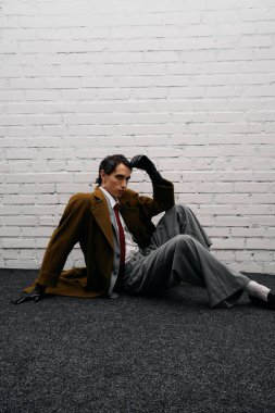 Şık bir adam şık kıyafetlerini ve kendine güvenen tavırlarını göstererek şık bir şekilde uzanır..