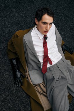 Gri takım elbiseli ve kırmızı kravatlı kendine güvenen adam modern bir şehirde rahat ederken şık görünüyor..