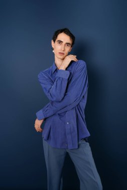 Modaya uygun bir adam duruşu olan, modaya uygun kıyafetini minimalist bir ortamda sergileyen.