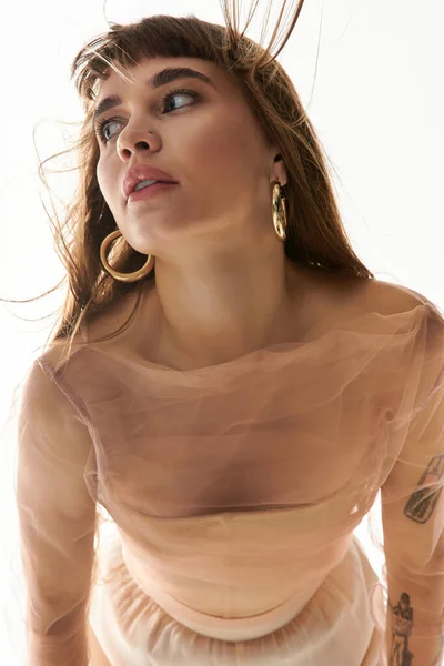 Красивая молодая женщина изящно позирует в стильном наряде, излучая уверенность и очарование. — стоковое фото