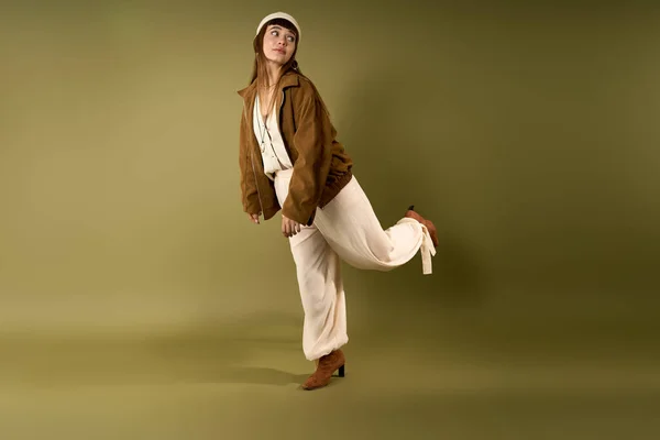 Pretty woman strikes a playful pose in fashionable attire against a soothing backdrop. — Stock Photo