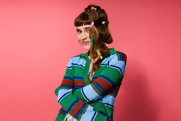 Eine fröhliche junge Frau mit verspielter Frisur posiert selbstbewusst vor rosa Hintergrund. — Stockfoto