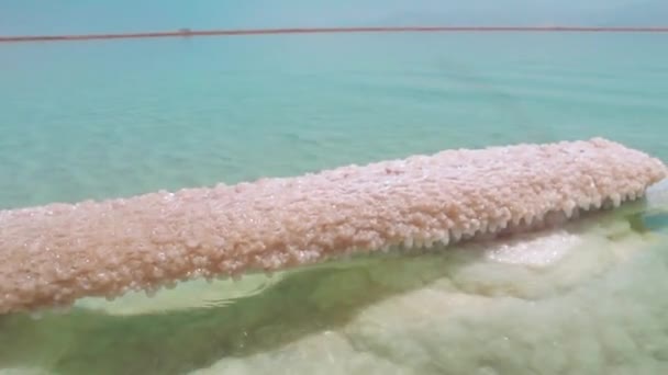 Filmagem em qualidade HD com o sal mineral do mar morto em israel contra o fundo do céu azul e montanhas. Água clara e transparente brilha ao sol — Vídeo de Stock