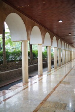 Klasik mimari tarzda sütunlar ve kemerler içeren koridor, simetrik ve zarif bir bina tasarımı sergiliyor