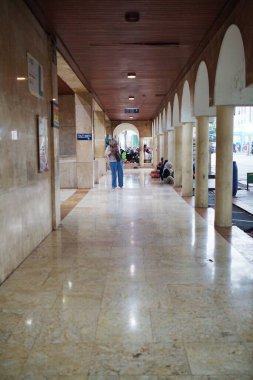 Bandung Endonezya - 21 Ekim 2025 Halka açık bir binanın iç koridoru mermer zemin ve kavisli sütunlar, koridorlarda yürüyen insanları gösteriyor..