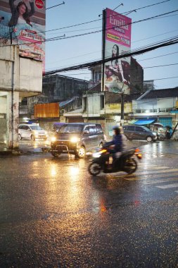 Bandung Endonezya - 21 Ekim 2025 Yağmurlu bir gecede araba farları yağmurlu yolda, Endonezya 'daki kentsel yaşamı gösteren bir şehir manzarası.