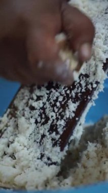 Geleneksel rendeleyici kullanarak mandalinayı elle rendeleyen birinin yakın çekimi, otantik Endonezya yemek hazırlığını gösterir