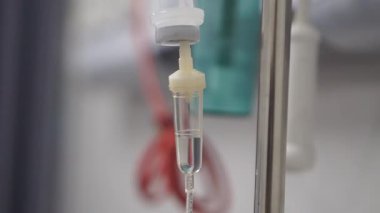 Hastane ortamında sürekli sıvı damlayan bir serum odasının yakın çekimi..