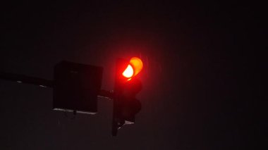 Yağmurlu bir gecede kırmızı trafik ışığı parlıyor.