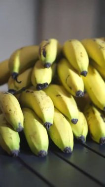 Bir yığın sarı Ambon muzunu siyah bir masada düzgünce yerleştirin.