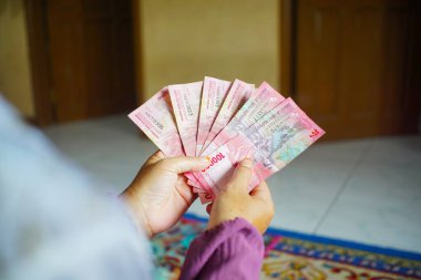 Finansal işlem yaparken kırmızı yüz bin rupia banknot sayan eller