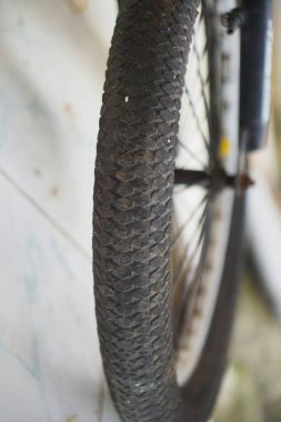 Tekerleğin üzerine monte edilmiş bir bisiklet lastiğinin ayrıntılı görüntüsü, kauçuk dokuyu ve bisiklet ekipmanlarını renklendiriyor.