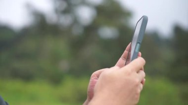 Akıllı telefon tutan bir adamın eli sık sık sosyal medyada kayan videolar görür.