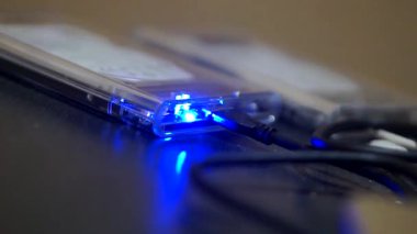 USB kablolar aracılığıyla bağlı şeffaf kaplama ile harici sabit diskler, veri transferi sırasında parlayan mavi gösterge ışıkları.