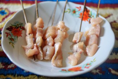 Çiğ et satay şiş ve baharatlı ızgara tabakta..