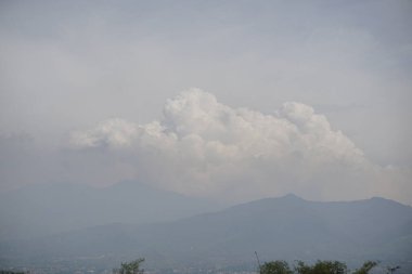 yumuşak beyaz bulutlar derin mavi gökyüzünde yüzüyor, doğanın güzelliğini ve zamanın akışını tasvir ediyor..