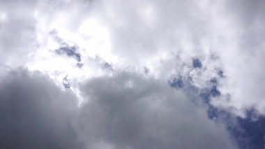 Yumuşak beyaz bulutların zaman çizelgesi derin mavi bir gökyüzünde sürükleniyor, doğanın güzelliğini ve zamanın akışını gösteriyor.