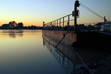 Gün batımında nehir nakliye mavnası. Romanya 'nın Nufaru kentinde günbatımında Tuna deltasında kargo mavnası.