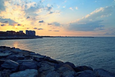 Köstence / Romanya; 07 / 04 / 2018. Köstence 'deki Three Slippers Beach' te (Rumence; Plaja trei papuci) dalgalar. Yazın günbatımında dalgakırandan şehrin manzarası.
