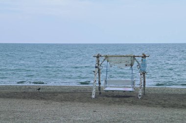 Romanya 'daki Olimp plajında güzel bir salıncak. Deniz manzaralı ahşap salıncak, dinlenmek için güzel bir yer..