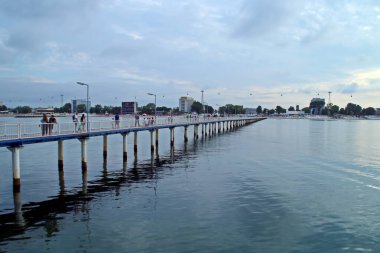 Romanya 'nın Constana kentindeki Mamaia Sahili' nde gezinen insanlar. Uzun, ahşap bir iskele. Orada yürüyebilirsin ve mükemmel bir sahil manzarası var..