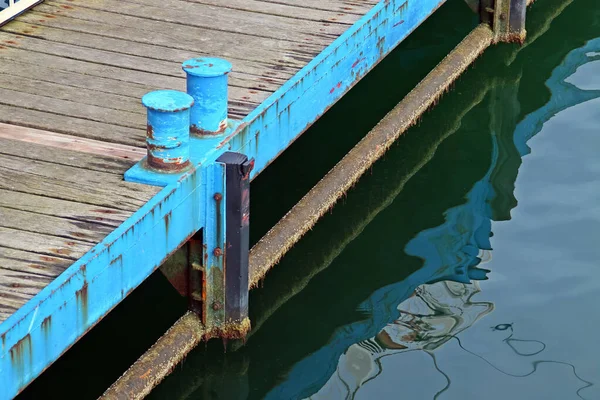 Mooring cleat on a wooden pier. Pier and surface of the water with the reflection of the pier on Mamaia Beach, Constanta, Romania.