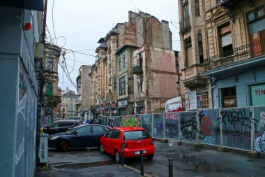 Bükreş, Romanya; 07 07 07 2018: Blanari Caddesi, Bükreş şehir merkezinin ihmal edilmiş caddeleri. Bozulmuş asfalt, grafiti kaplı duvarlar ve yağmurlu bir günde kablo karışıklığı genel bir yıkım bakışı verir..