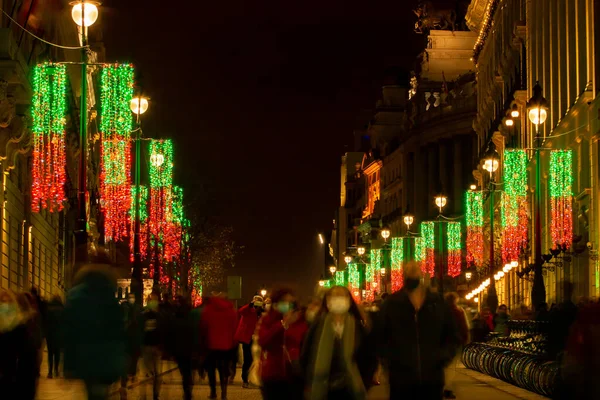 Christmas illumination of Alcala street in Madrid, Spain. People walking at night in this historic street with Covid19 masks. November 28, 2020.