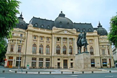 Bükreş, Romanya; 07 08 2018. Bükreş Üniversitesi Merkez Kütüphanesi ve Kral I. Carol 'un binicilik heykeli. Bükreş Devrim Meydanı 'nda bina ve heykel bulunuyor.