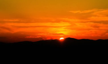 İspanya, Madrid 'de, Sierra de Guadarrama' da gün batımı. Güneşin son ışınlarıyla turuncu gökyüzü Madrid 'in kuzeyindeki dağların siluetini aydınlatıyor..