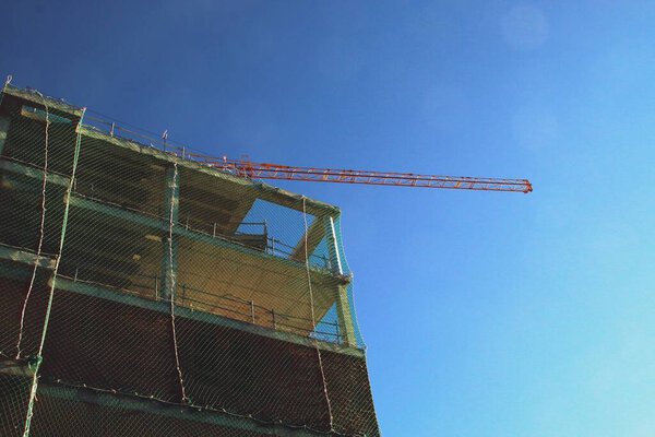 A building under construction in the Montecarmelo neighborhood, Madrid, Spain. Construction crane, scaffolding and protective nets in one working day.