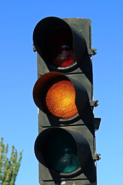 Madrid, İspanya 'da San Modesto caddesinde Amber trafik ışığı. Arka planda mavi gökyüzü olan arabalar için kehribar trafik ışığı yakın plan.