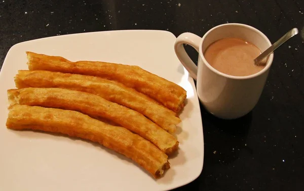 Four spanish porras. Spanish food like spanish churros and a cup of cocoa with hot milk.