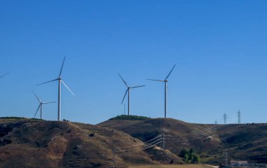 Tepedeki elektrikli rüzgar türbinleri. Rüzgar enerji parkı, yenilenebilir enerji..
