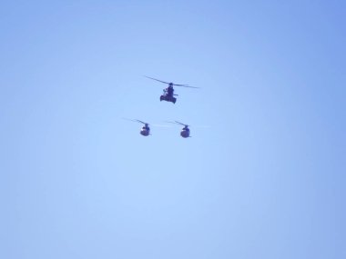 Helikopterler açık bir gökyüzünde düzenle uçuyorlar. İspanyol Hava Kuvvetleri 'nin üç helikopterinin silueti..