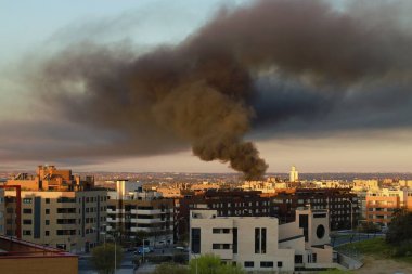 Madrid, İspanya. 03 24 2021. Montecarmelo mahallesindeki Monasterio de las Huelgas caddesinde bir endüstriyel depoda yangın. Güneşin doğuşuyla Madrid semalarında kara duman bulutu.