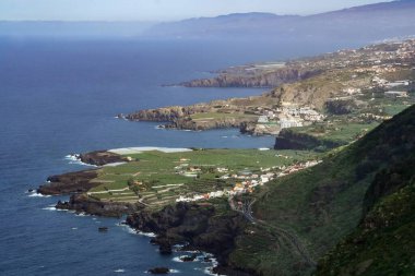 İspanya 'nın Tenerife adasının kuzey kıyısında. Daha az sarp alanların ev ve muz tarlaları yapımında kullanıldığı volkanik adanın tipik kıyı manzarası..