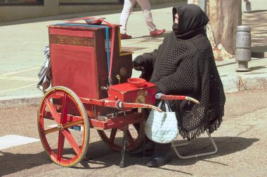 Madrid, İspanya; 04 04 2021. Madrid 'in geleneksel org çalan yaşlı kadın. Pazar pazarında geleneksel elbiseli ve yas tutan yaşlı bir kadın..