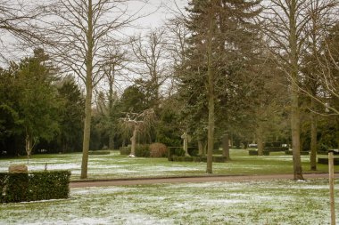 Kopenhag Batı Mezarlığı kışın. Halk parkının karlı bahçesindeki çalıların ve çimlerin arasındaki mezar taşları. Danimarka.