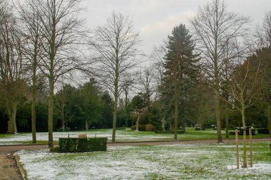 Kopenhag Batı Mezarlığı kışın. Halk parkının karlı bahçesindeki çalıların ve çimlerin arasındaki mezar taşları. Danimarka.