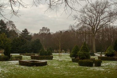 Kopenhag Batı Mezarlığı kışın. Halk parkının karlı bahçesindeki çalıların ve çimlerin arasındaki mezar taşları. Danimarka.